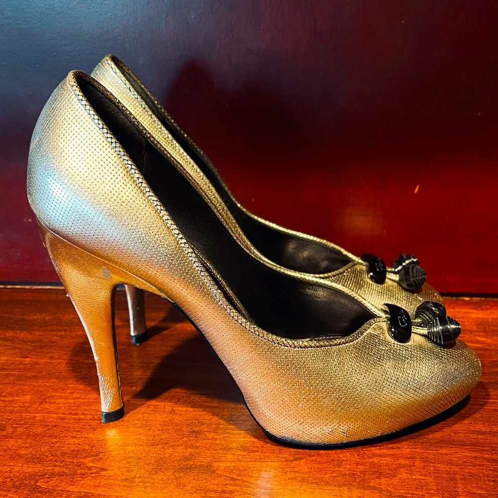 Giorgio Armani gold leather pumps with signature black embellishments.